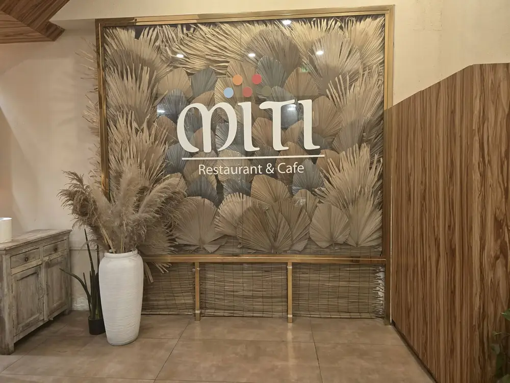 The Miti Restaurant and Cafe signage set against a wall of dried palm fans