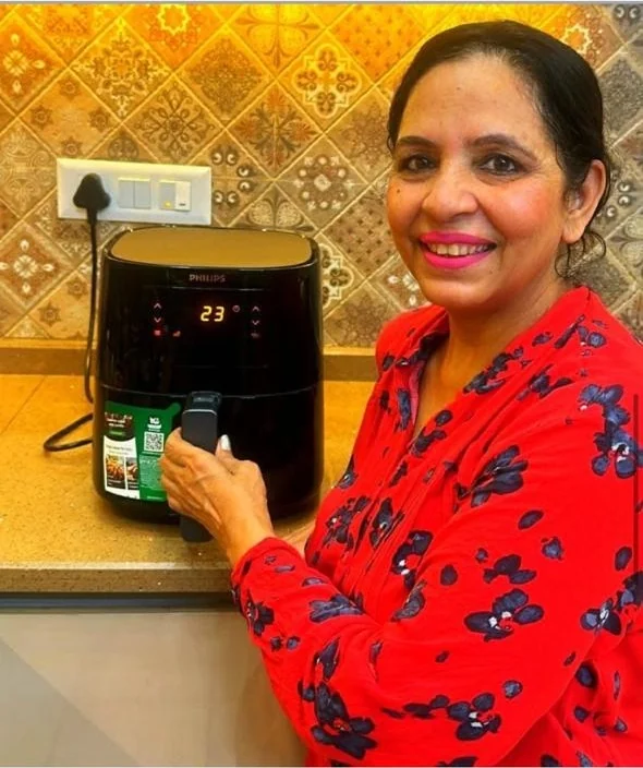 Laddi Dhingra standing at her kitchen counter beside the Philips air fryer she won, a year after the competition